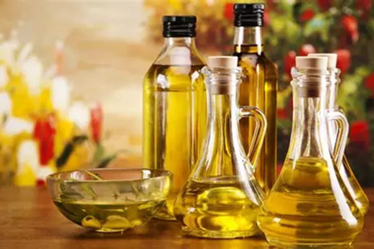 Bouteilles et carafes en verre remplies d’huiles végétales sur une table en bois